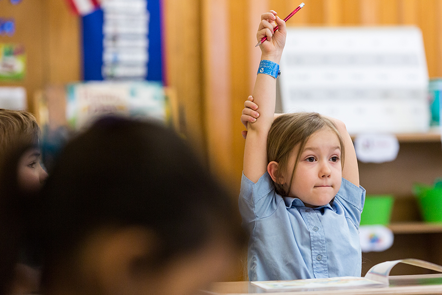 First Grade. Student enthusiastically raising her hand